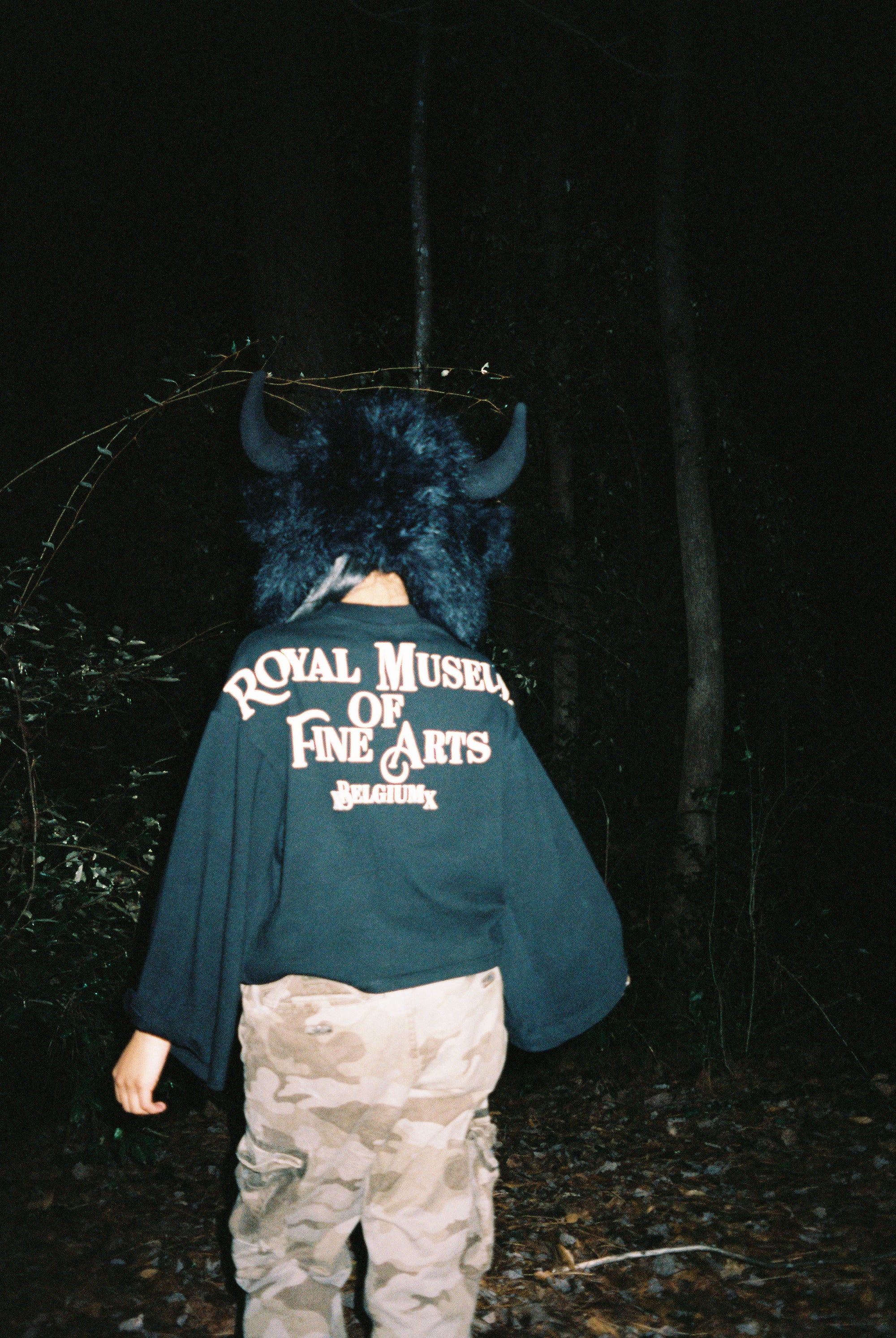 Person wearing a blue hoodie with text, lying on dark ground