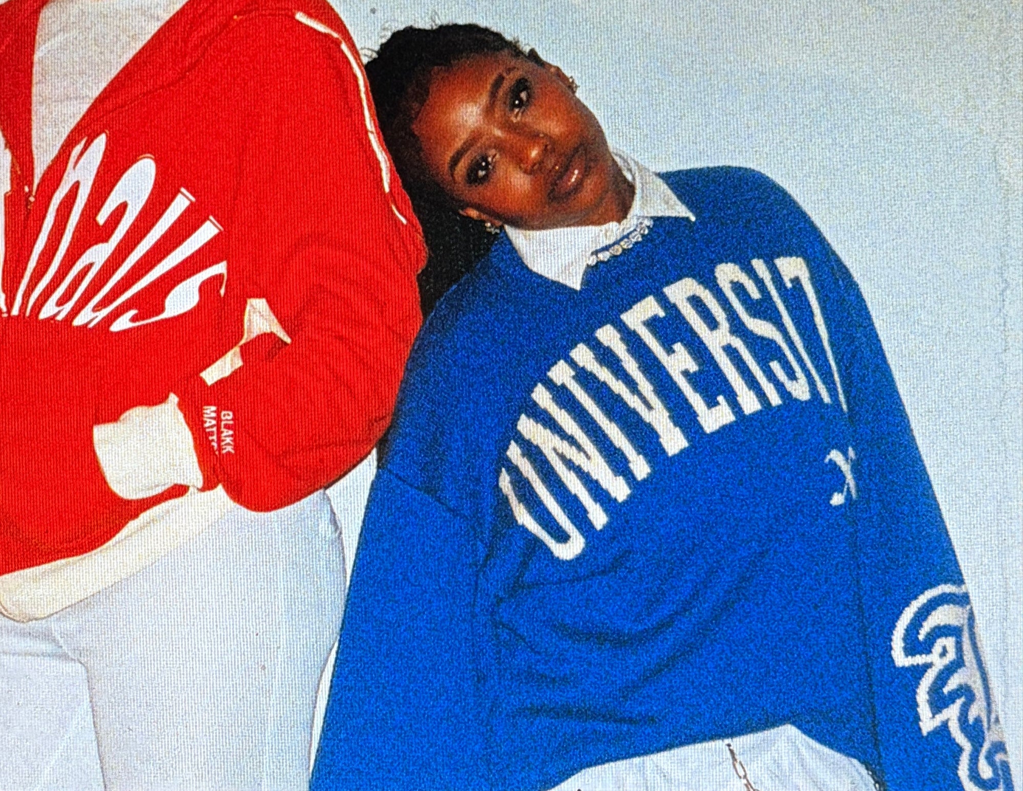 Two people wearing red and blue sweatshirts with visible branding.